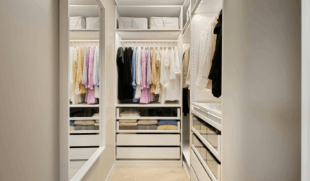 Modern walk-in wardrobe interior in Australia at a home served by True Blue Glass, showing neatly organised clothing on hanging rails, built-in drawers and shelves with a clean, minimalist storage design.